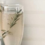 Champagne flutes with rosemary, bottle, pitcher, lemons. Elegant cocktail setup for a celebration.